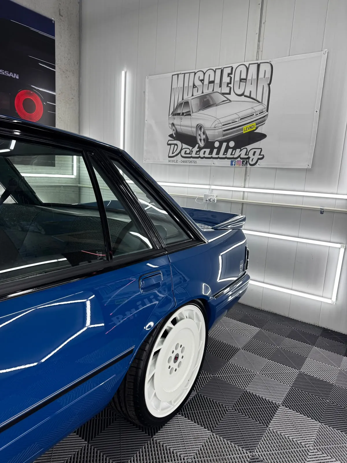 Blue Holden VL Commodore parked beneath the Muscle Car Detailing banner